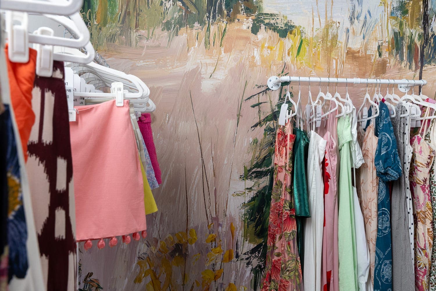 Racks of curated dresses along the hand-painted mural at the BORROW studio